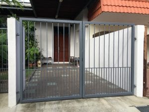 A metal gate in the driveway of a house.