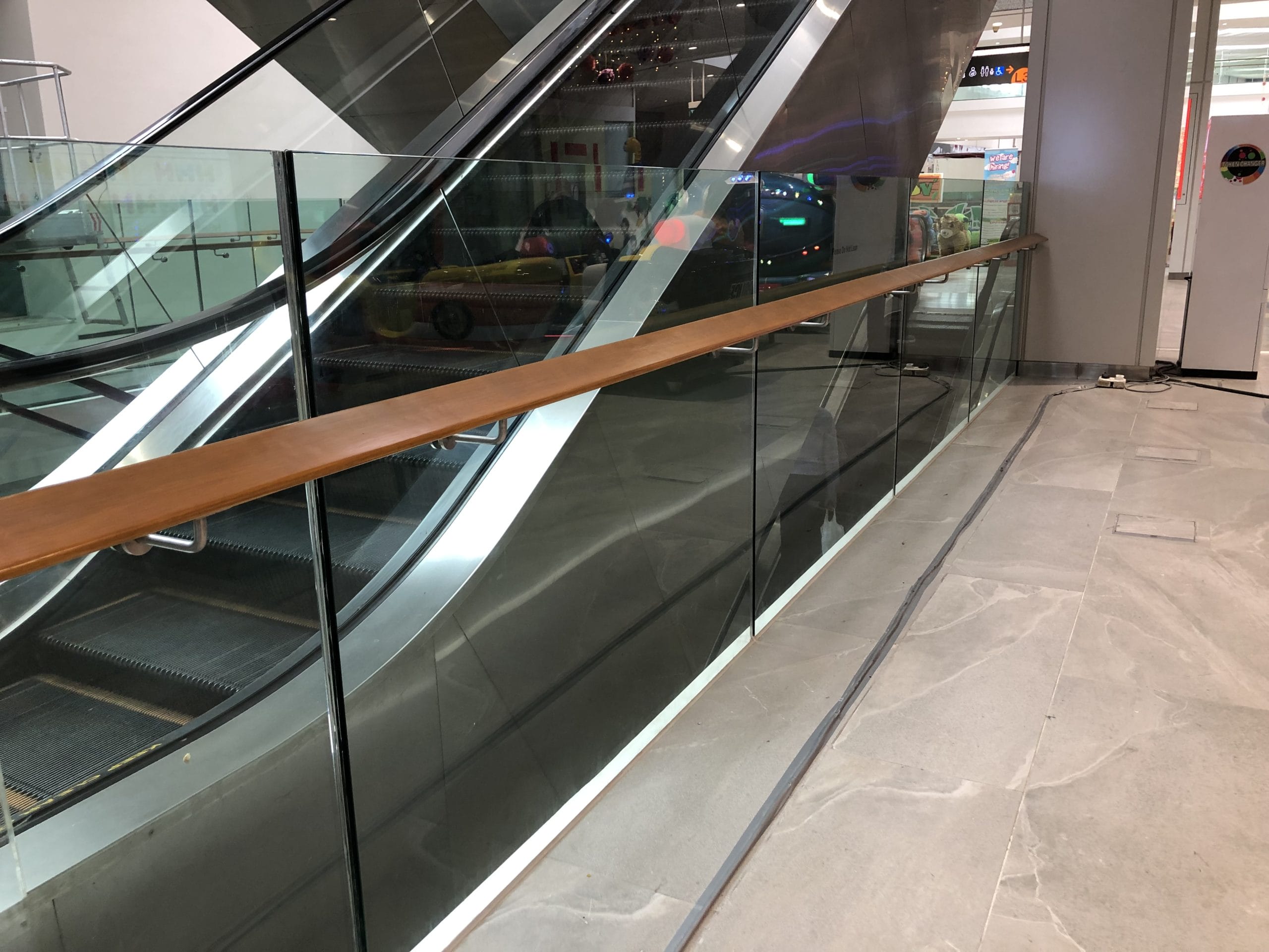 A glass railing near an escalator in a commercial property.